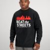 A young man wearing a black sweatshirt with BEAT the STREETS PHILADELPHIA printed in white and red paired with gray sweatpants