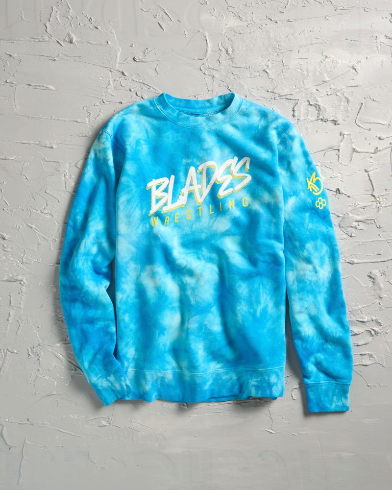 A vibrant blue tie-dye sweatshirt featuring the bold text BLADES WRESTLING printed in yellow along with a logo on the sleeve