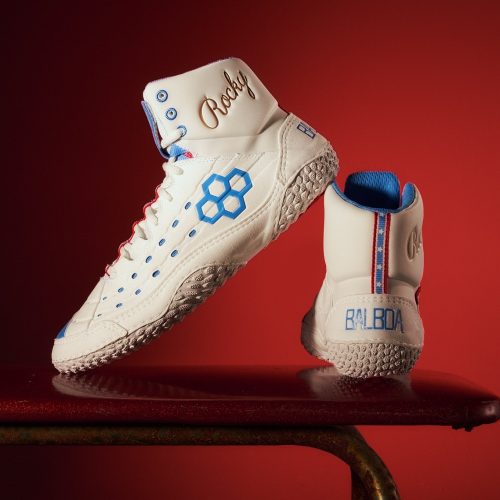 Classic white high-top sneakers featuring blue accents and the name Rocky embossed on the ankle displayed against a striking red background