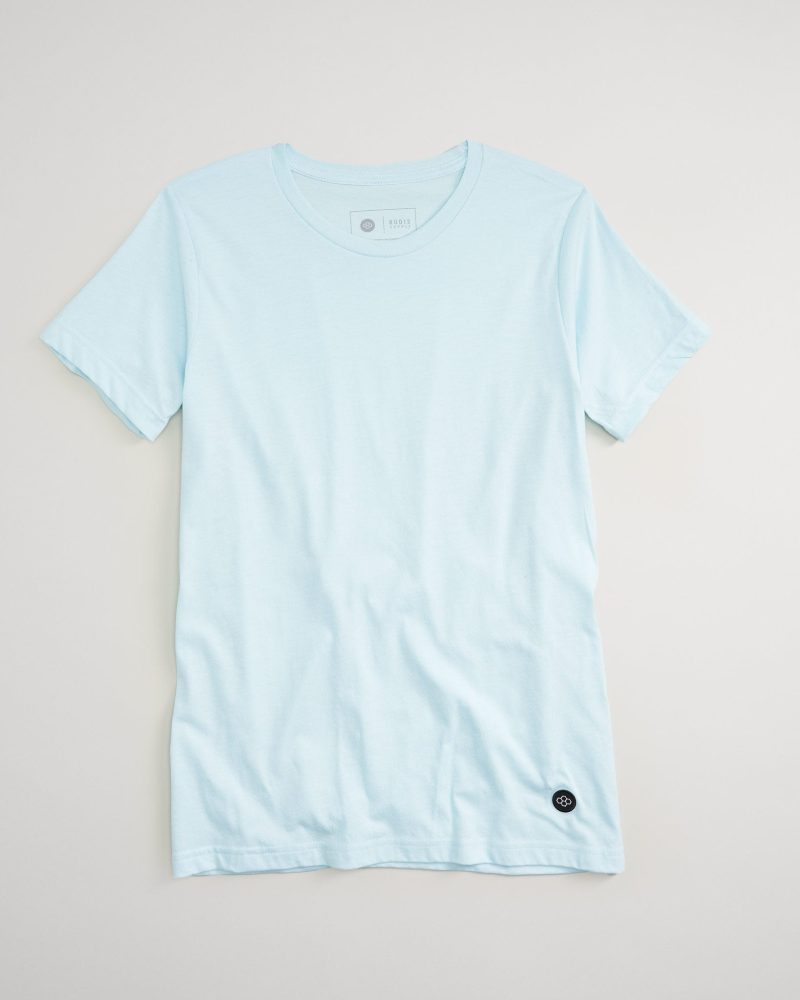 A light blue short-sleeved t-shirt displayed against a neutral background featuring a simple crew neckline and a subtle logo on the bottom left side