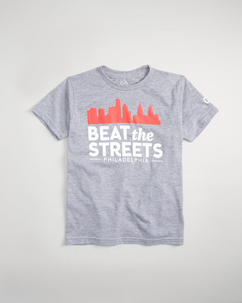 A gray t-shirt featuring a graphic design that includes the text BEAT the STREETS along with a silhouette of city buildings and the word PHILADELPHIA